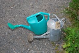Two watering cans, one galvanised and one plastic (both with roses).