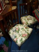 A pair of dining chairs with floral seats.