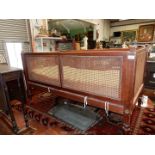 A Mahogany framed child's Cot/Bed having caned side and end panels and standing on turned legs,
