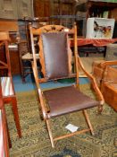 An unusual hardwood framed folding Armchair upholstered with dark brown simulated leather seat and