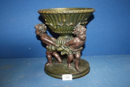 A composite table Centrepiece of a bowl supported by three cherubs, 10 1/4" tall x 9 1/2" diameter.