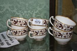 Six Derby teacups with berry and foliage decorated borders with gold highlights.