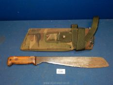 A 1979 military machete/knife with wooden handle in camouflage sheath, '120-92-+2'.