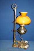 A brass oil lamp converted to electric on adjustable stand with amber glass shade, 24 1/2" tall.