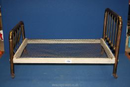 A Victorian dolls bed with brass ends, wooden frame and wire mesh base,