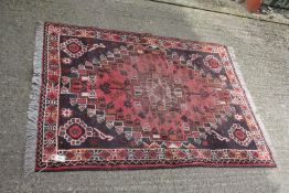 A dark pink and purple/navy ground rug with geometric pattern border and fringing 61" x 42".