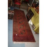 A burgundy and black ground Runner, with border pattern and fringing, 120'' x 34'' approx. maximum.