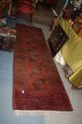 A burgundy and black ground Runner, with border pattern and fringing, 120'' x 34'' approx. maximum.