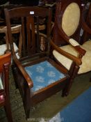 An Oak framed open armed Commode Chair with inset blue fabric upholstered seat, furnished.