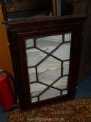 A dark Oak wall hanging Corner Cabinet having a 13 pane geometrically glazed door,