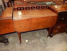 An Oak Pembroke Table standing on tapering turned legs terminating in brass castors,
