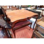 A serpentine sided Mahogany Table standing on canted cabriole legs terminating on brass castors,