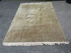 A very large sage green Rug having subtle petal shape relief and cream fringing, 11' x 6" x 8' 3".