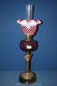 A dual wick brass Corinthian column oil lamp with cranberry glass reservoir and cream swirl shade,