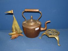 A copper kettle, brass trivet and a brass model of a sailing boat.