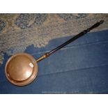 A copper bed warmer with engraved flower design to lid, wooden handle, 41" long.