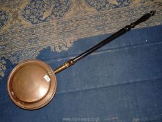 A copper bed warmer with engraved flower design to lid, wooden handle, 41" long.