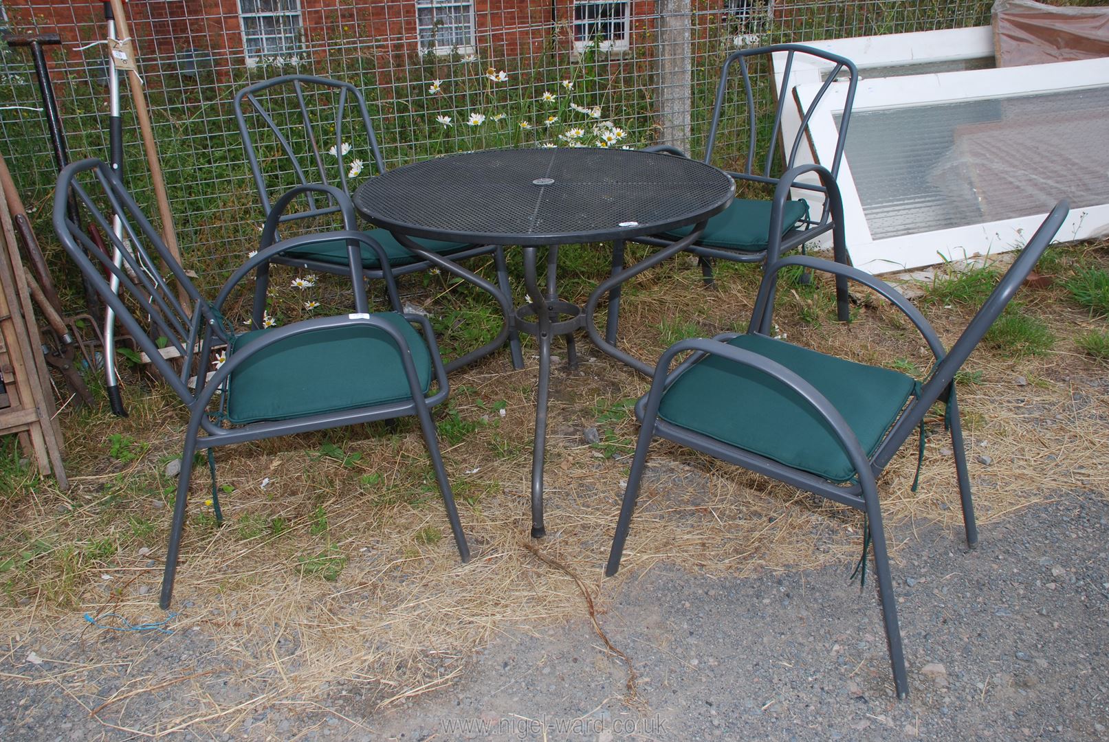 A metal garden table and four chairs with green cushions approx. 35 1/2" (d) x 28".
