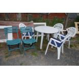 A white plastic garden table and four chairs with blue cushions, plus two plastic folding chairs.