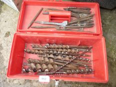 A red tool box containing wood-boring bits/augers.