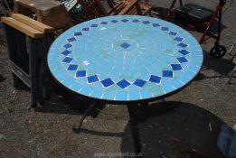 A round tiled top garden table with metal base.