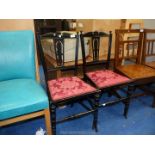 A pair of hall chairs with carved central splat and red upholstered seats.