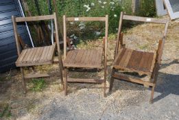 Three folding wooden chairs.