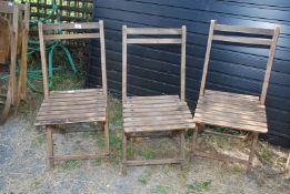 Three folding wooden chairs.