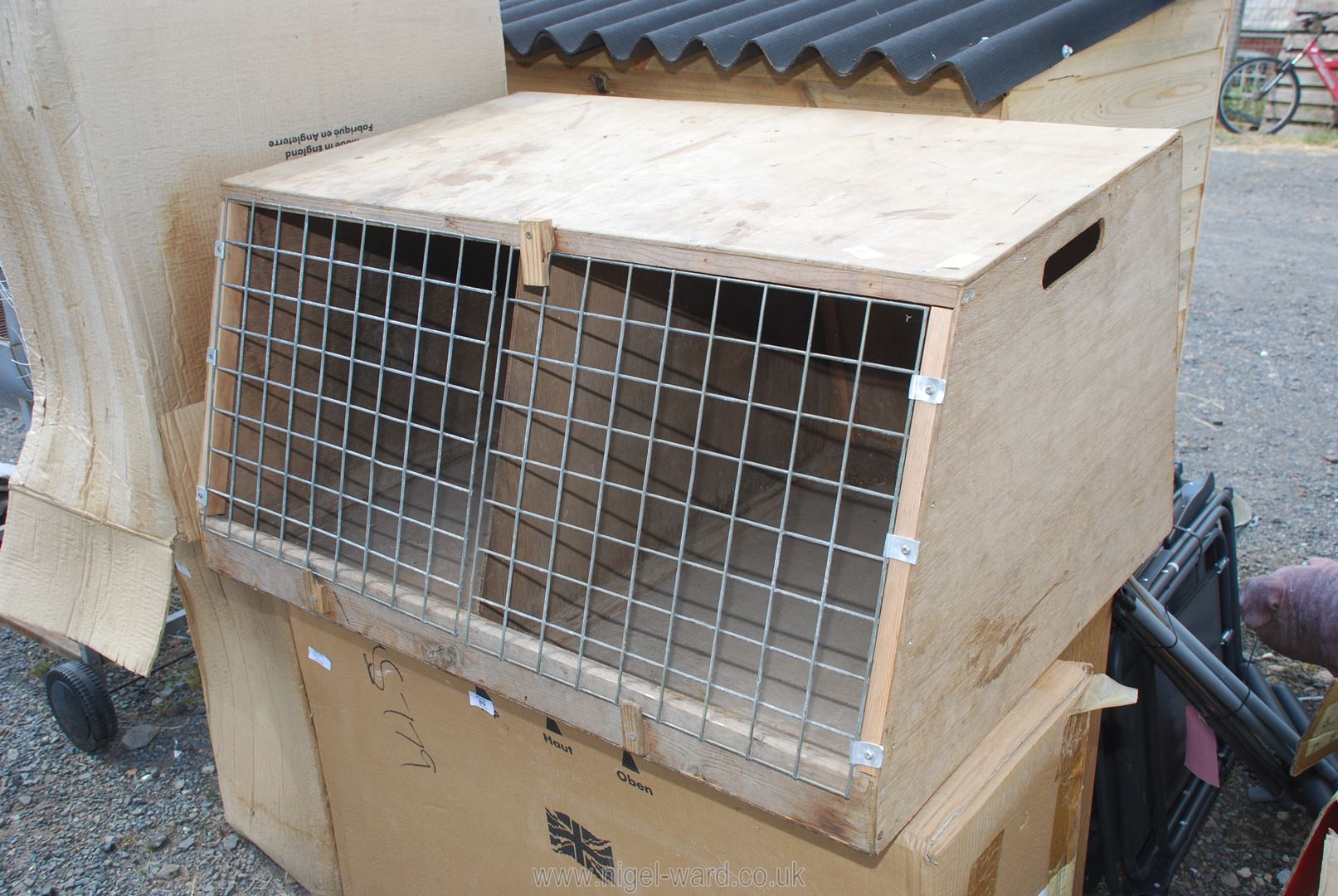 A wooden double dog crate with mesh doors.