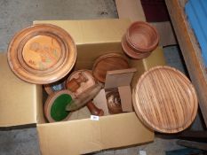 A box of Treen containing wooden turned bowls, cheese board and dome, cake stands etc.