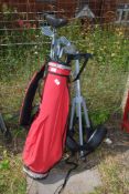 A golf caddy and trolley with clubs including Howlson, etc.