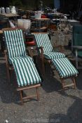 A pair of teak and brass steamer chairs with cushions.
