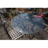 An ornate iron based glass topped table and three chairs, 3' 7 1/2" diameter x 2' 3 1/2" high.