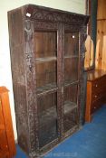 A darkwood floor standing glazed front bookcase with carved detail to door frames and front,