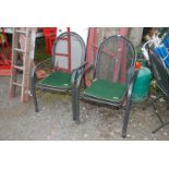 A pair of metal garden chairs with green and cream cushions.