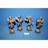 A set of four cast metal Putti each playing a musical instrument in differing poses on bases,