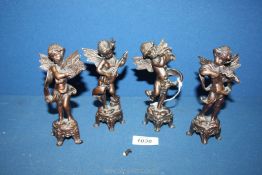 A set of four cast metal Putti each playing a musical instrument in differing poses on bases,