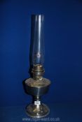 A metal based Oil lamp with glass chimney, single burner, 23'' high overall.