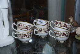 Six Derby teacups with berry and foliage decorated borders with gold highlights.