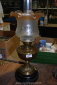 A brass Oil lamp on heavy plinth base with etched glass shade that tints to light brown at the