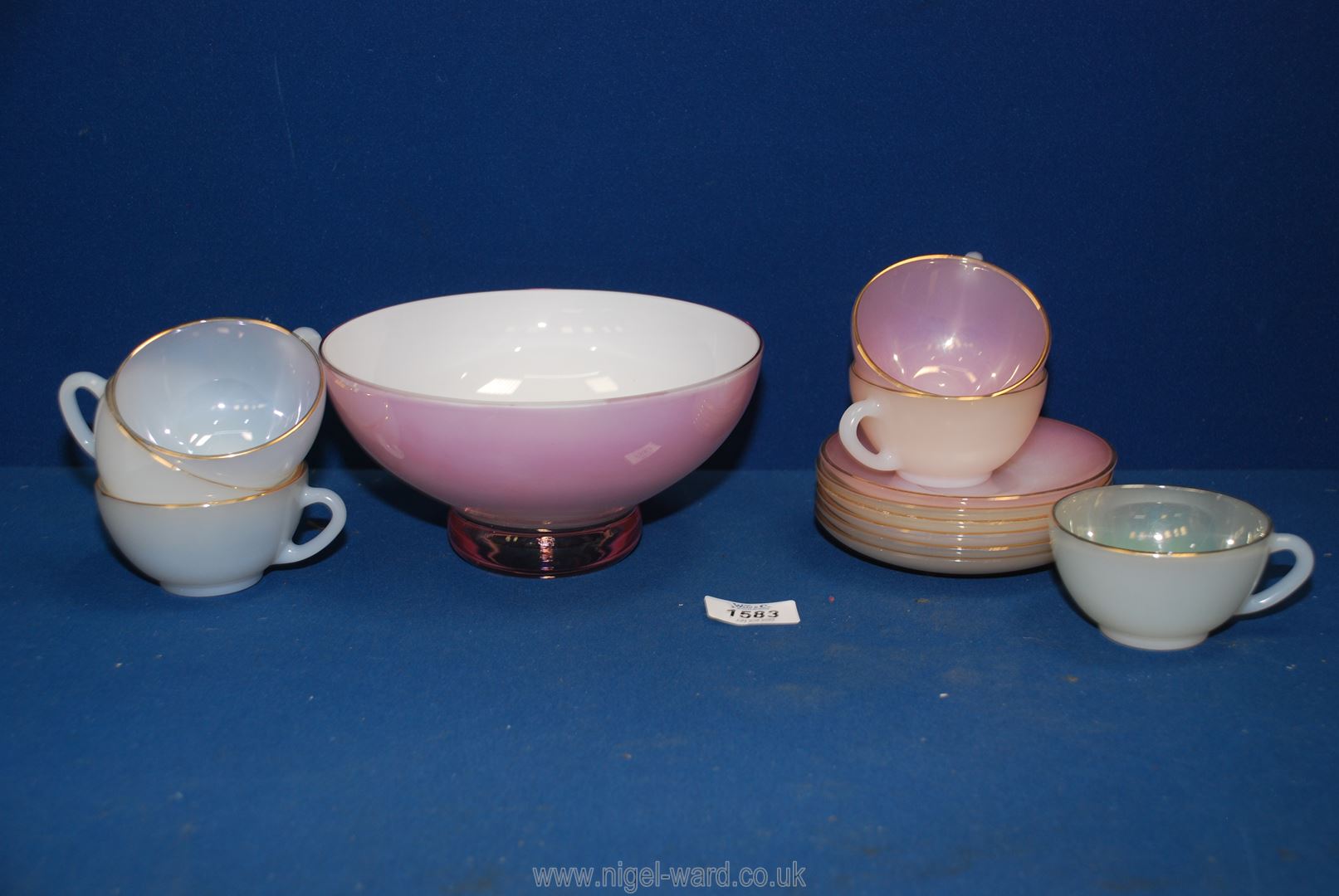 A pink glass bowl with white interior and six Arcopal cups and saucers.