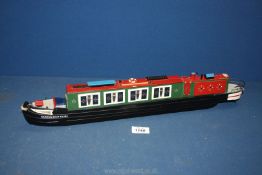 A wooden model of Barge with 'Narrow Boat Tours' painted on the side, in green, red and black,