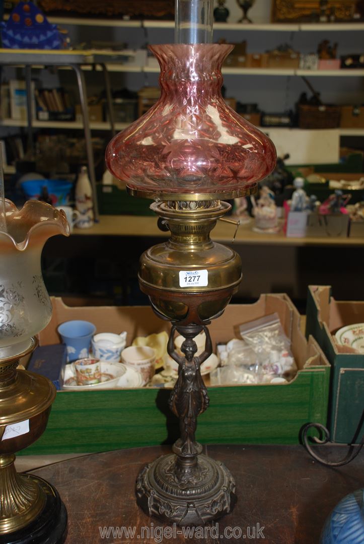 An unusual Oil lamp on cast metal base in the form of a lady with brass reservoir and pale
