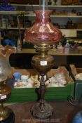 An unusual Oil lamp on cast metal base in the form of a lady with brass reservoir and pale