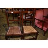 A pair of cane seated darkwood bedroom chairs having light and darkwood stringing.