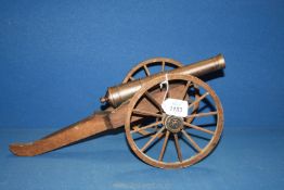 A large Model Cannon with iron barrel and wood chassis and wheels,