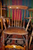 A traditional solid Elm seated kitchen carver chair having stickback turned legs and 'H' stretchers.