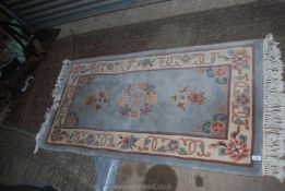 A Kayam fringed rug in oriental floral pattern, blue ground and cream border, 60 1/2" x 31".