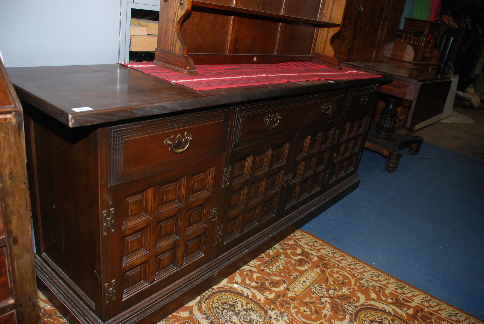 A contemporary darkwood Sideboard having three frieze drawers with brass shaped back plate drop