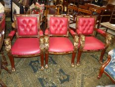 A set of three elegant open-armed hall Armchairs strikingly upholstered in red with buttoned back